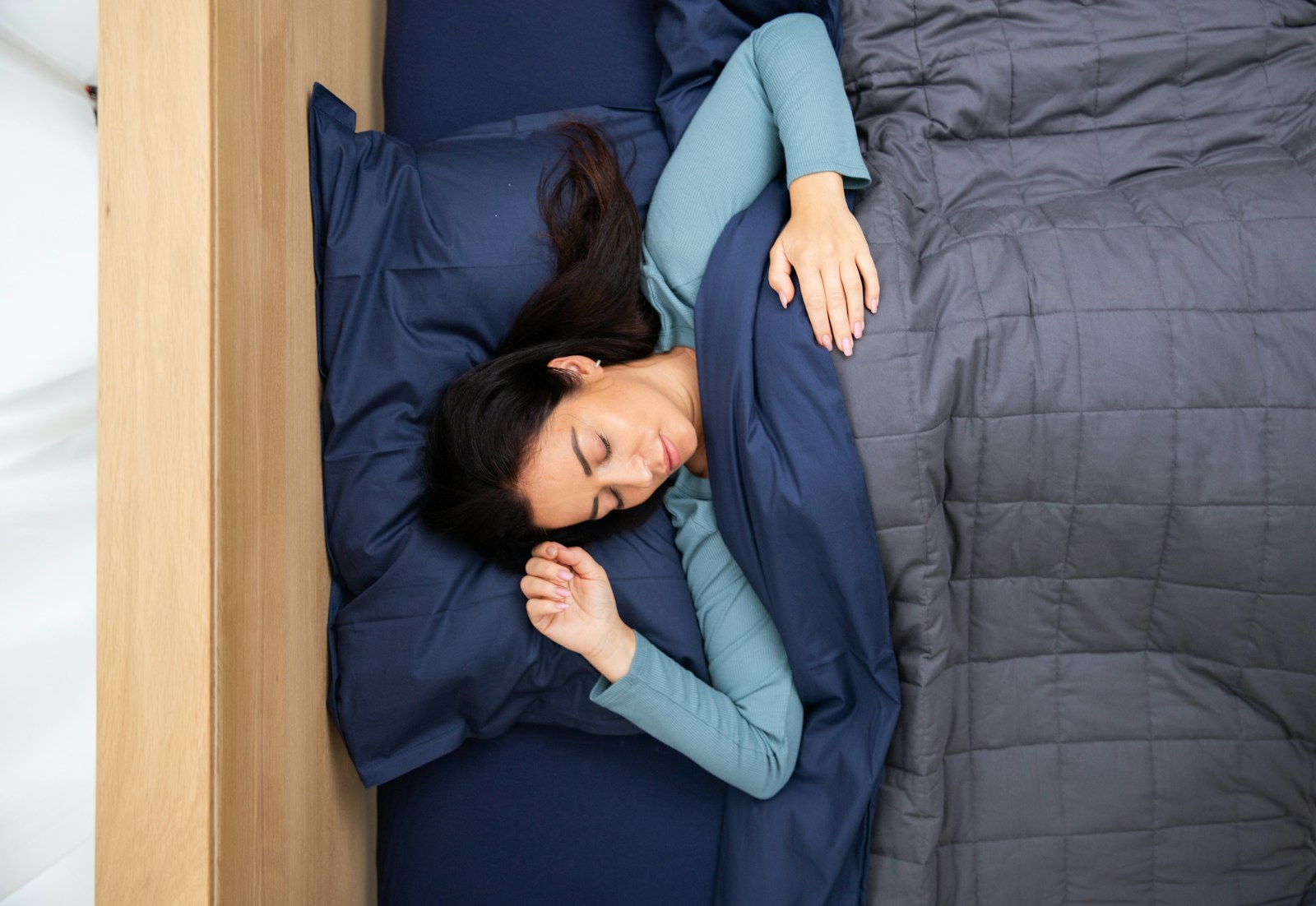 Woman sleeping in a bed with a blue duvet